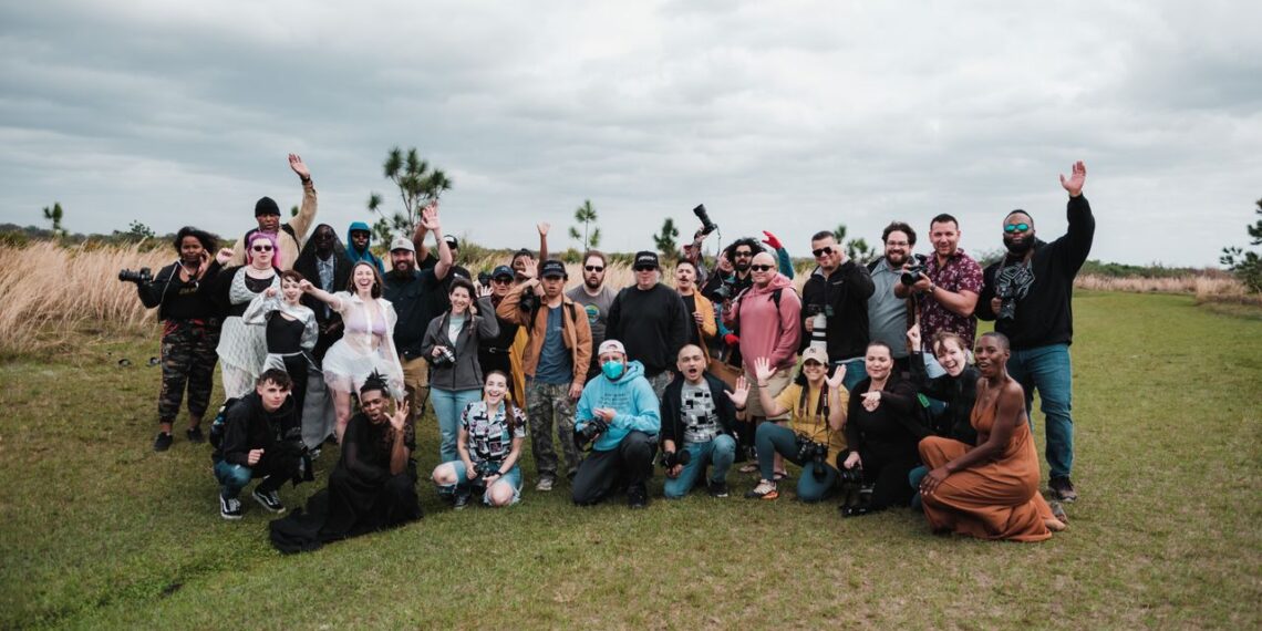 A diverse group of photographers posing together in a natural setting with cameras.