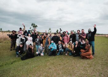 A diverse group of photographers posing together in a natural setting with cameras.